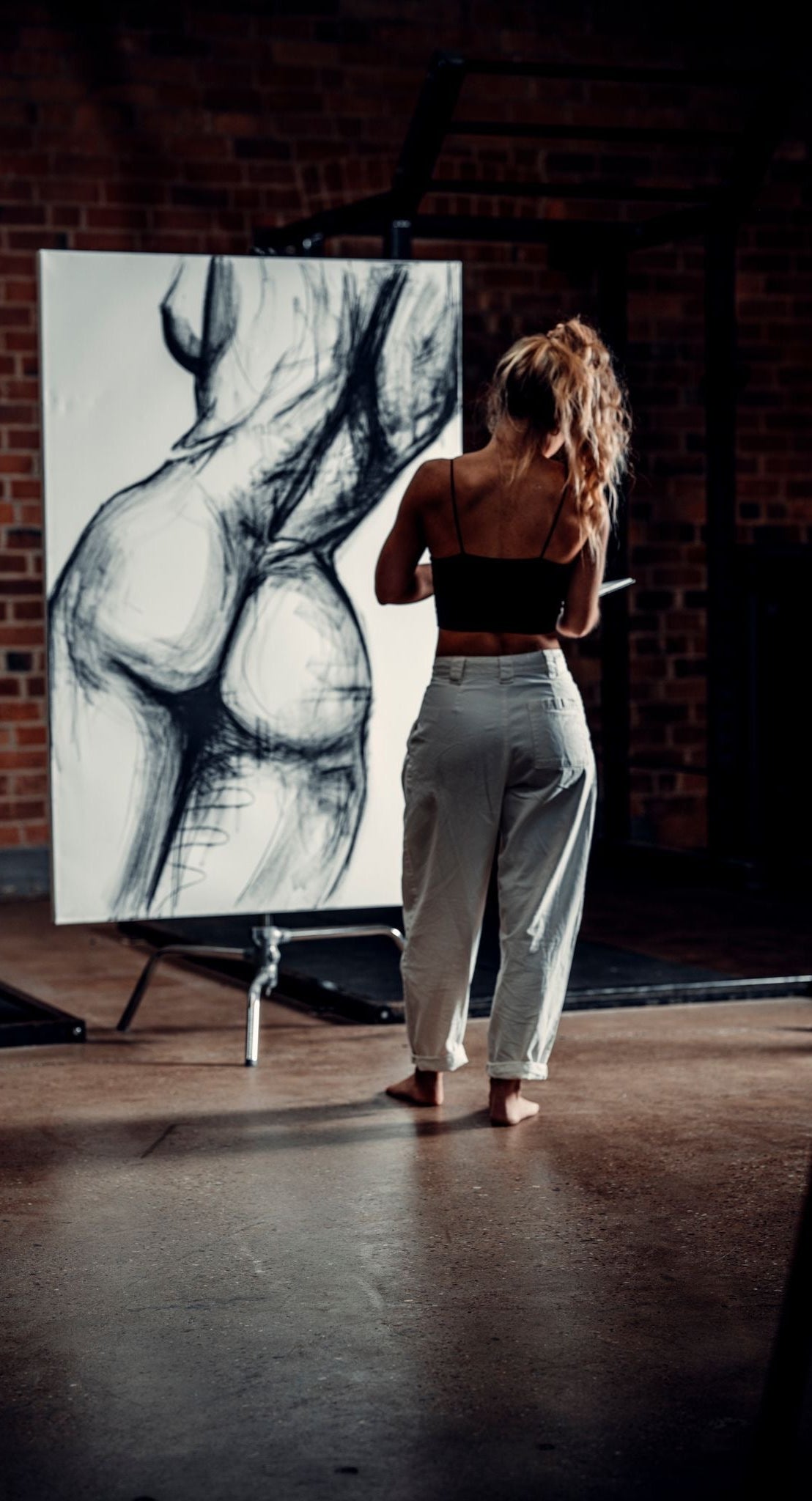 London Artist Briony May Richardson from StudioBMR in Essex. Drawing a large scale canvas piece with charcoal with painted elements. XL nude figure artwork. Monochrome figurative Art.