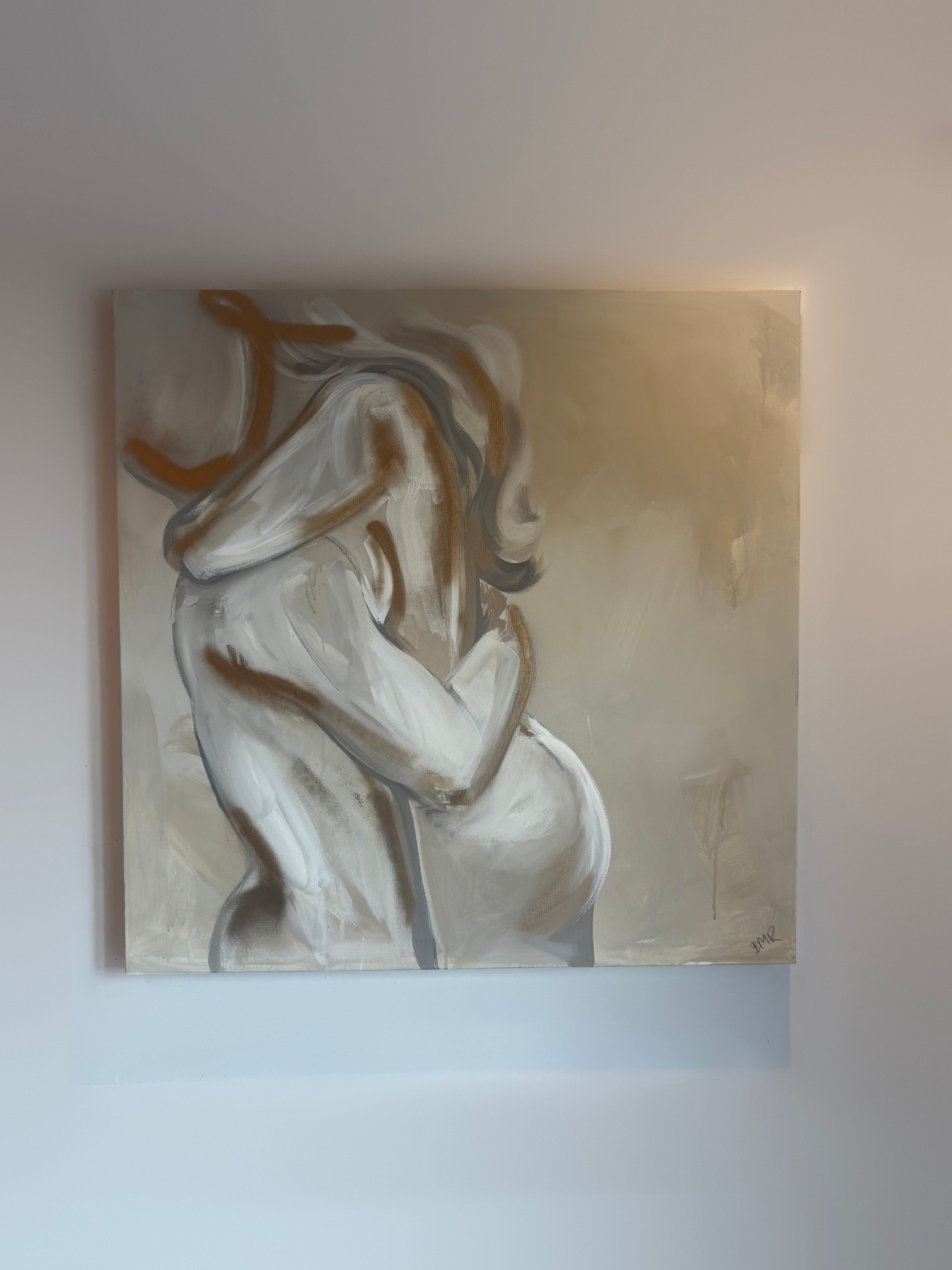 UK artist Briony May Richardson has hand painted this soft and romantic neutral beige, white and grey toned painting of a man and woman hugging. The painting features gold elements and is quite abstract in style.